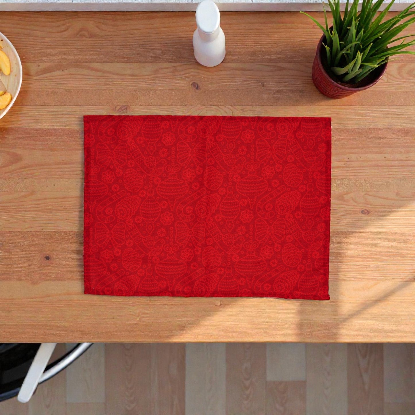 Tovaglietta di Natale rossa Melin in tessuto con motivi natalizi, su un piano in legno