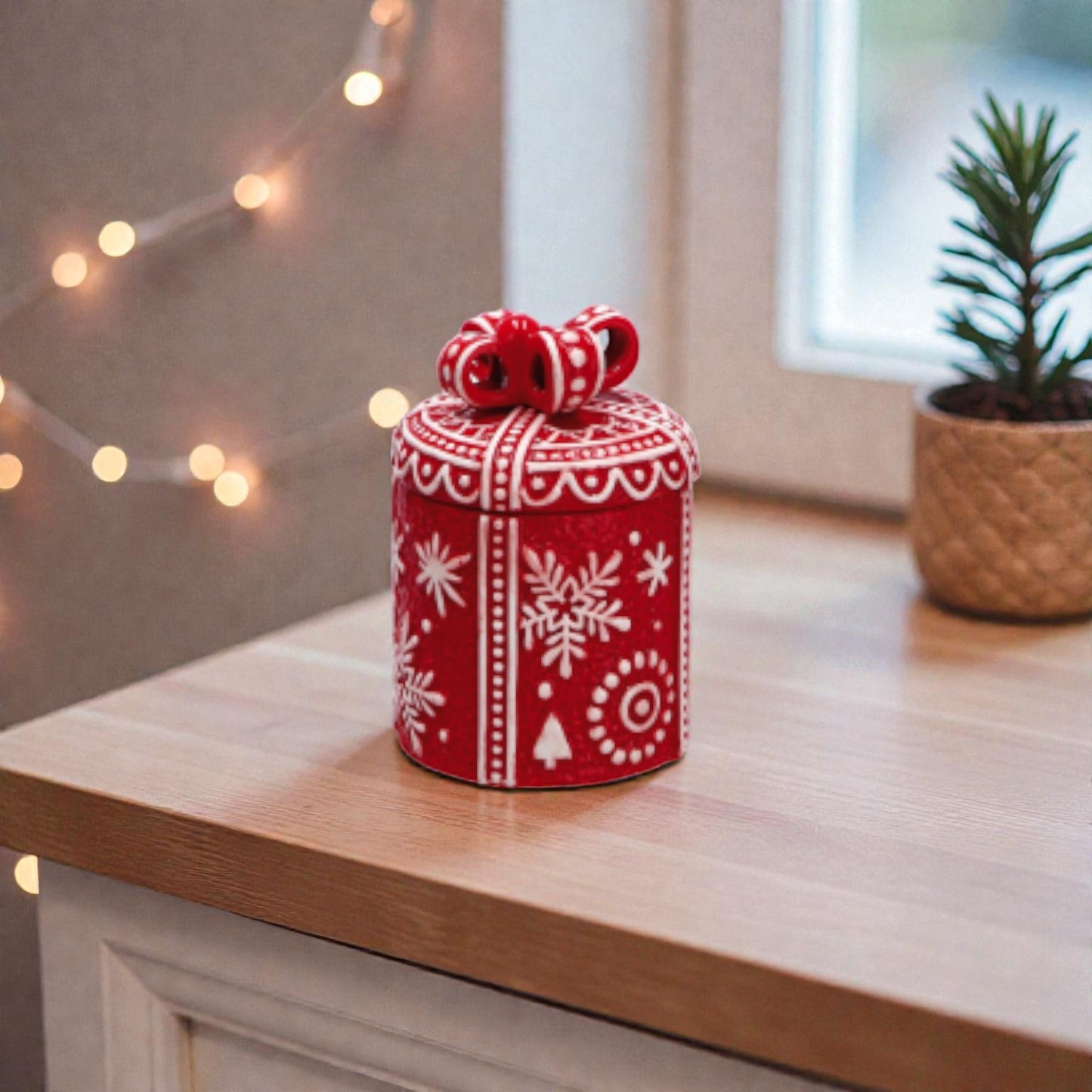 Contenitore cilindrico rosso in ceramica con tema natalizio, ambientato in una cucina a Natale.