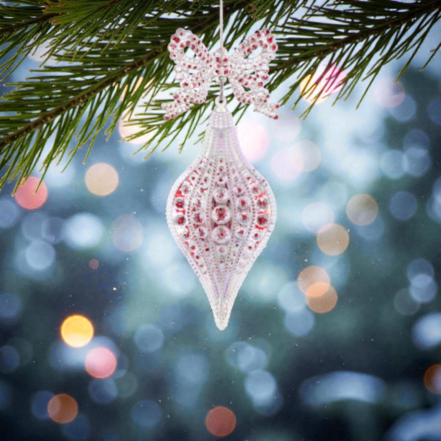 Decorazione albero di natale in acrilico trasperante e rossa, appesa ad un albero di natale.