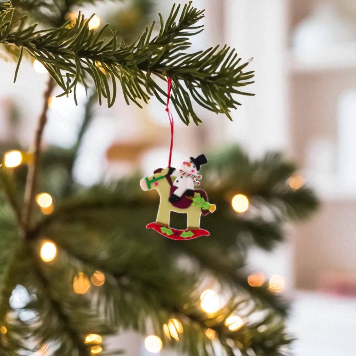 decorazione di natale con cavallo e pupazzo di neve appeso ad un ramo di albero di natale, con sfondo natalizio in una casa calda