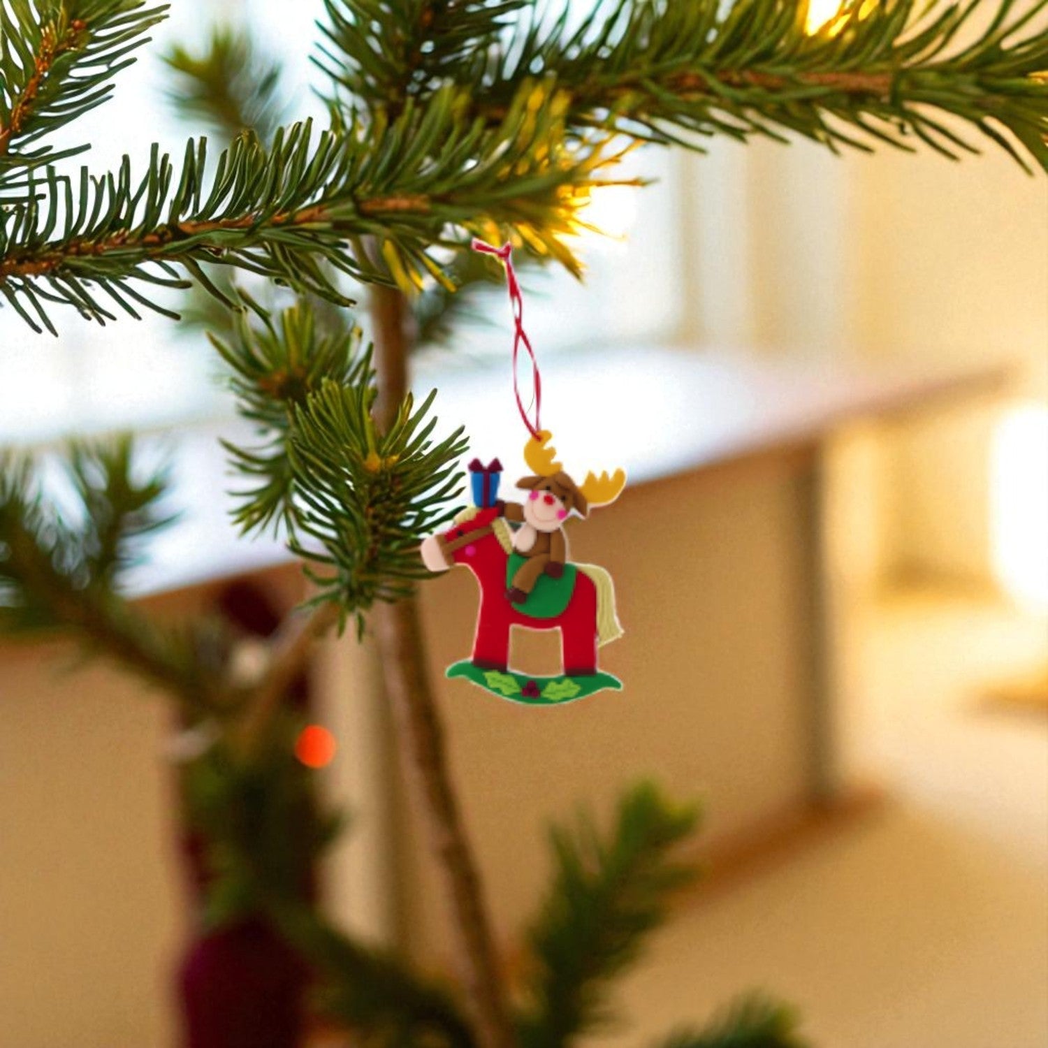 renna che cavalca un cavallo a dondolo, decorazione natalizia da appendere all'albero di natale. Sfondo sfoncato bokeh a tema natalizio, in una casa calda.