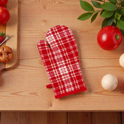 Guanto da cucina rosso a tema natalizio un piano in legno con piante e pomodori.