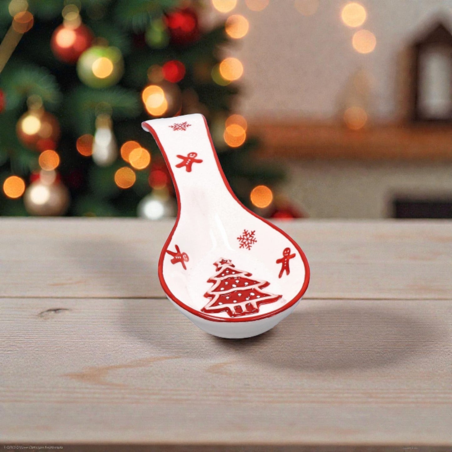 Porta cucchiaio di Natale rosso e Bianco sopra un piano cucina in legno con sfondo natalizio.