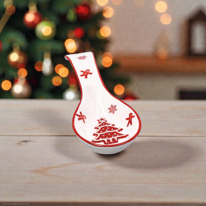 Porta cucchiaio di Natale rosso e Bianco sopra un piano cucina in legno con sfondo natalizio.