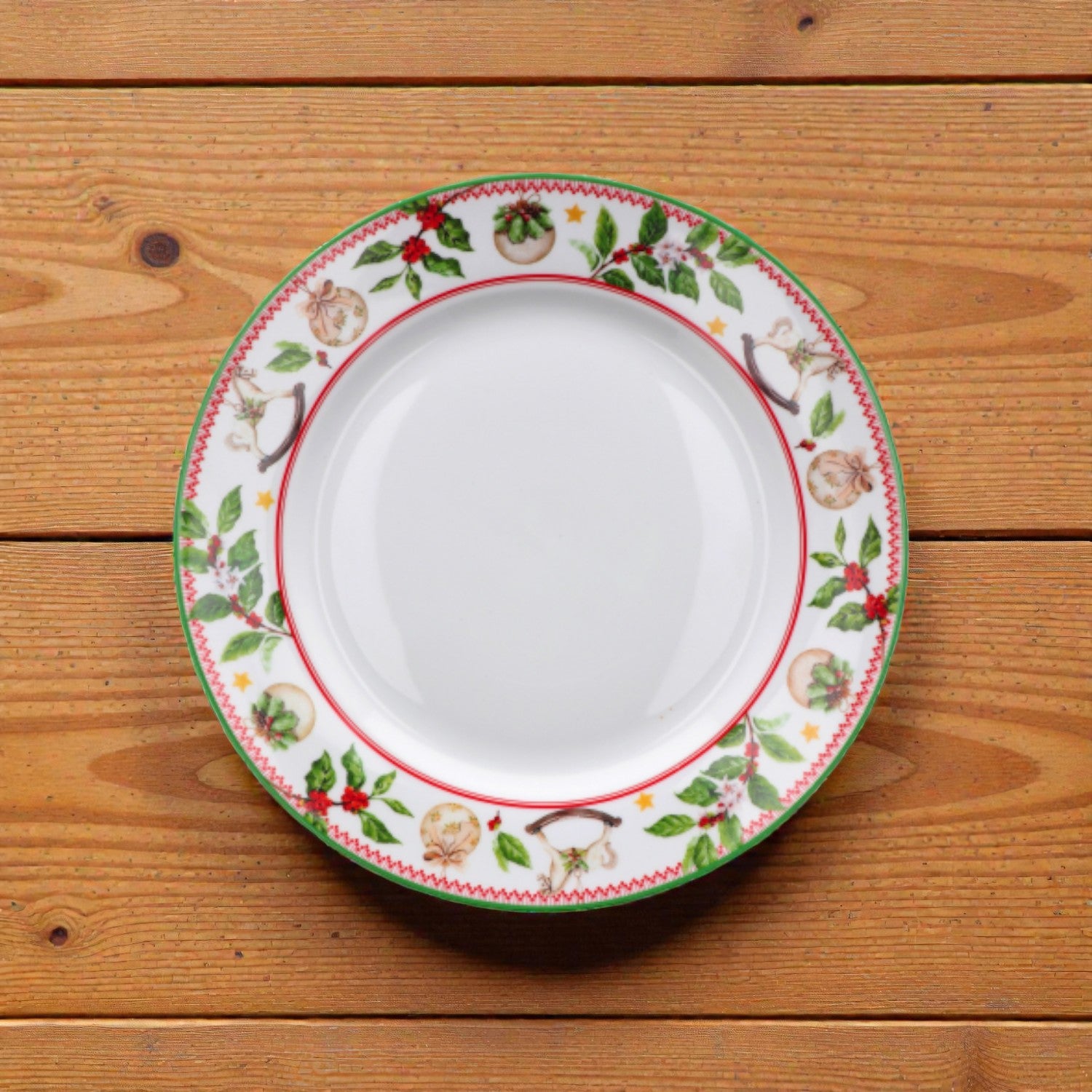 Piatto di natale con rig rossa e verde e disegno di vischio natalizio su un piano in legno.