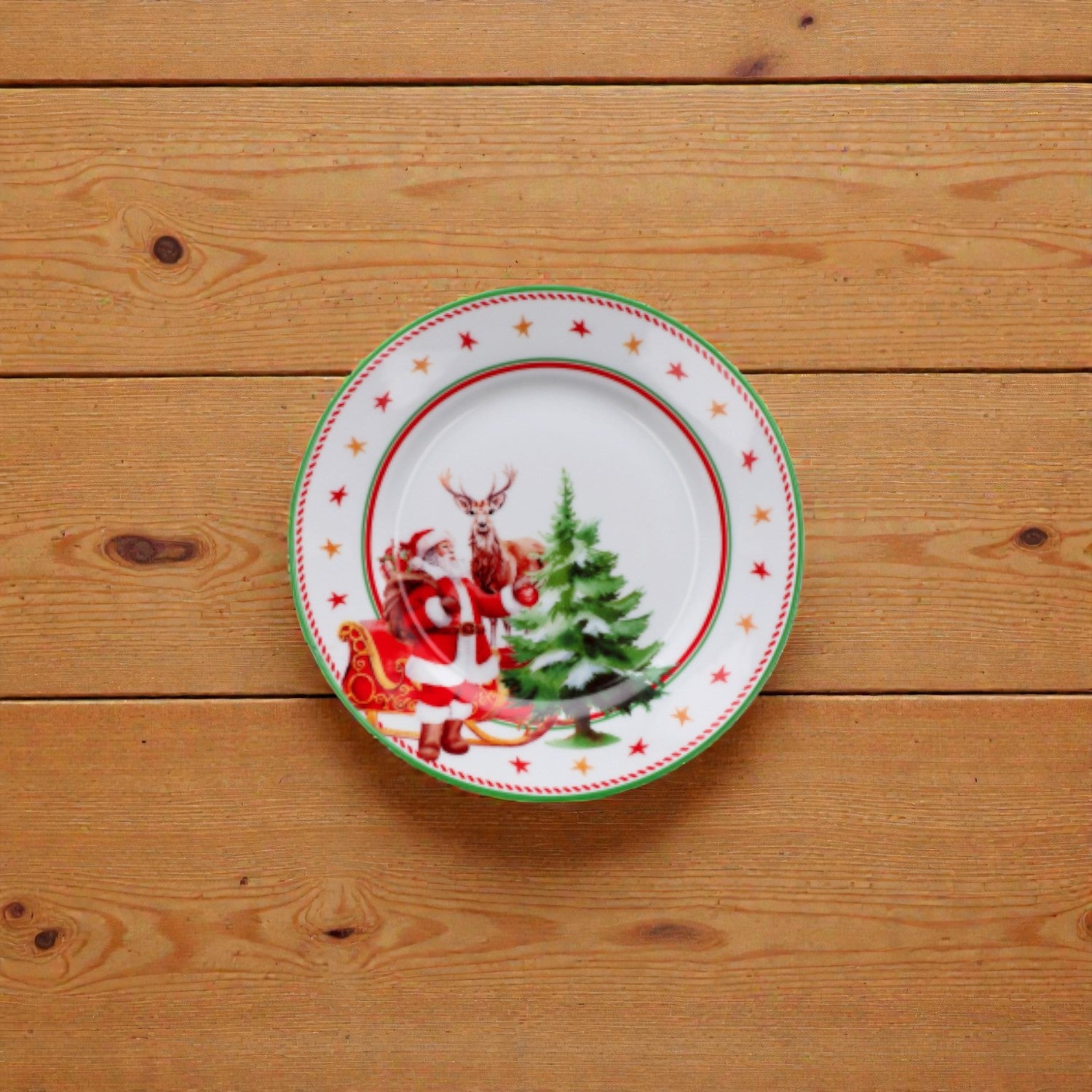 Piatto di natale bianco con righe rosse e verdi con disegno babbo natale e slitta su un piano in legno.