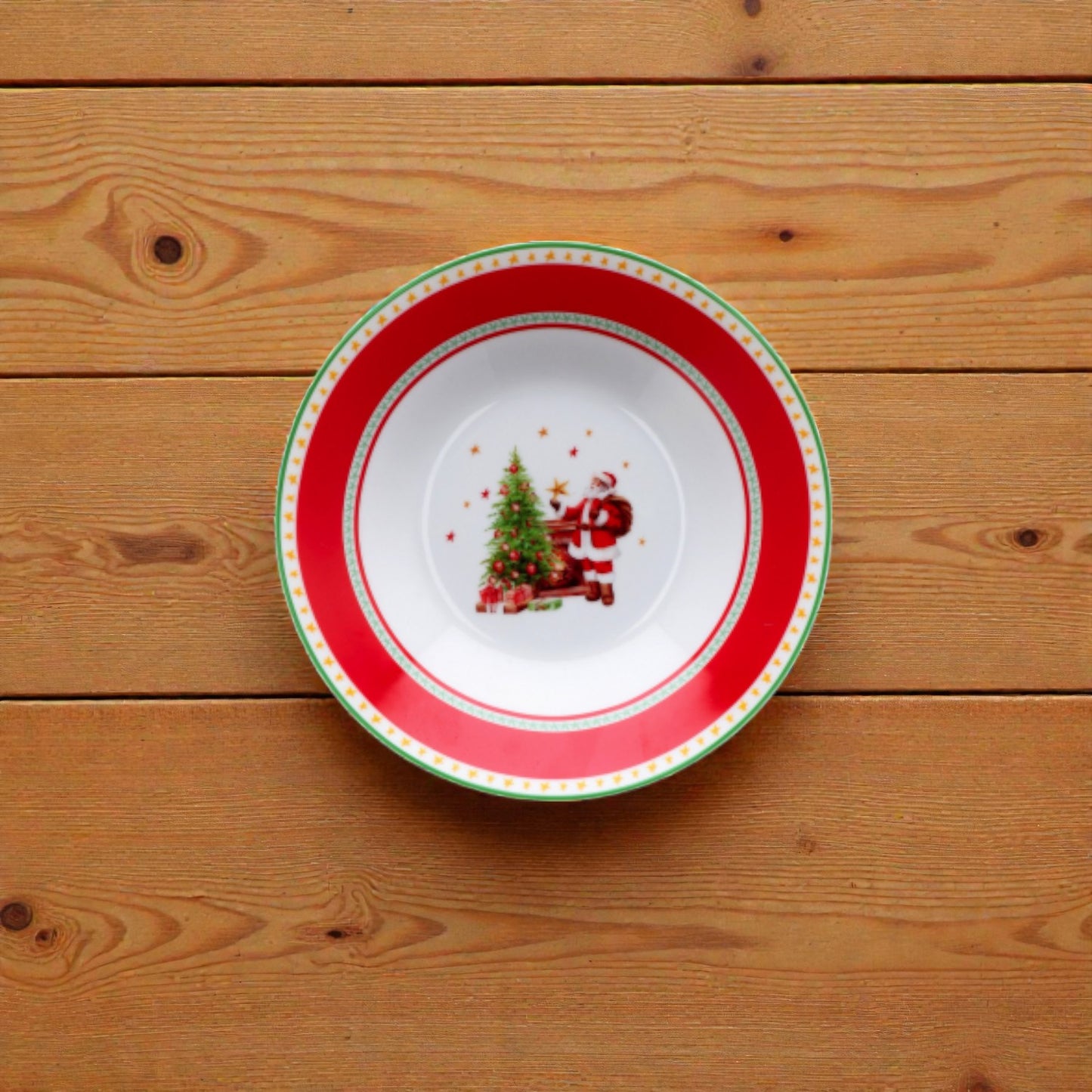 Piatto di natale bianco con righe rosse e verdi con disegno babbo natale su un piano in legno.