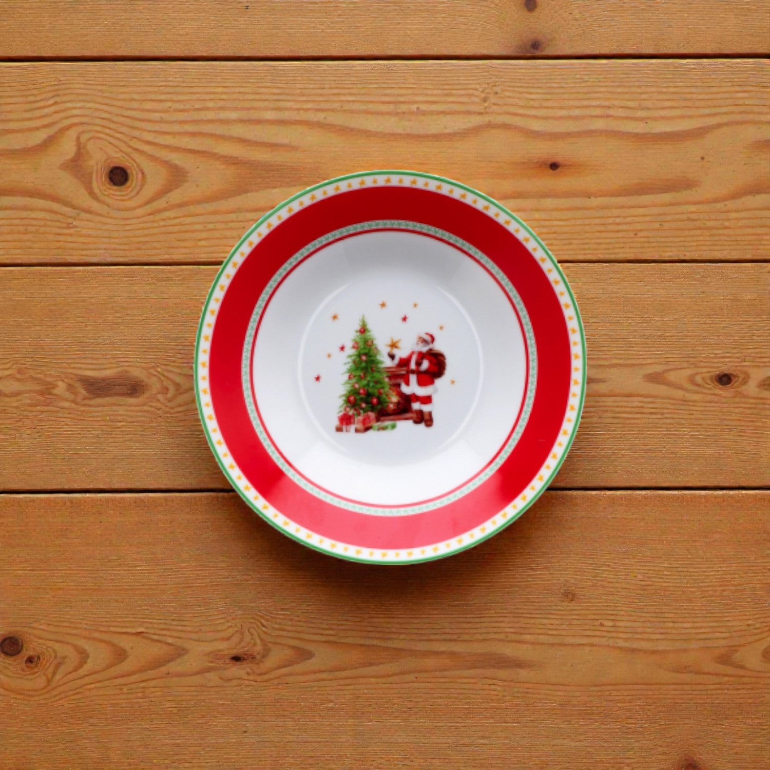 Piatto di natale bianco con righe rosse e verdi con disegno babbo natale su un piano in legno.