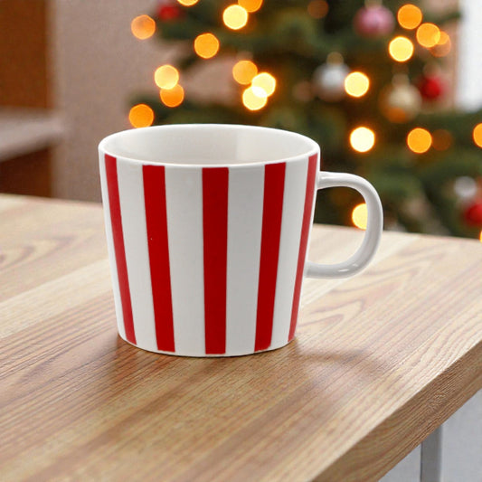 Tazza di natale in ceramica bianco e rosso con disegni di natale su un piano in legno in una casa festiva.