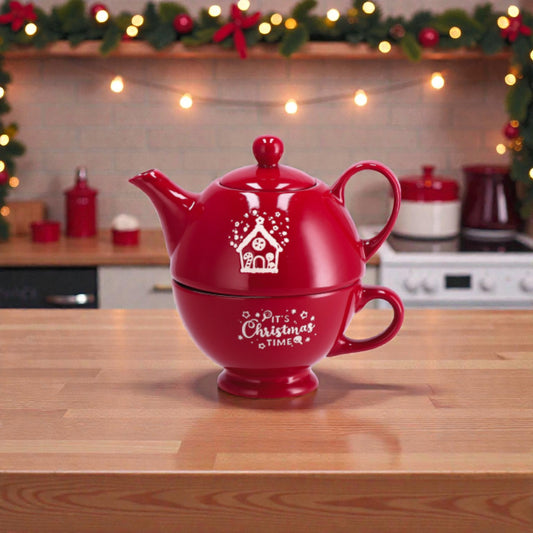 Combo tazza e teiera corby rossa che si possono impilare, con illustrazione a tema natalizio, ambientate su un piano in legno in una cucina festiva e accogliente.