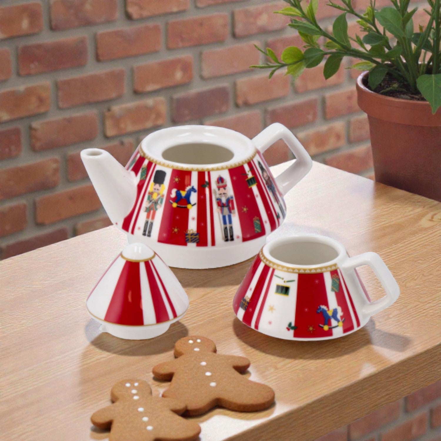 Kit teiera impilabile di natale con tazza, con illustrazioni rossa e illustrazione schiaccionoci su un piano in legno, ambientato in una casa luminosa