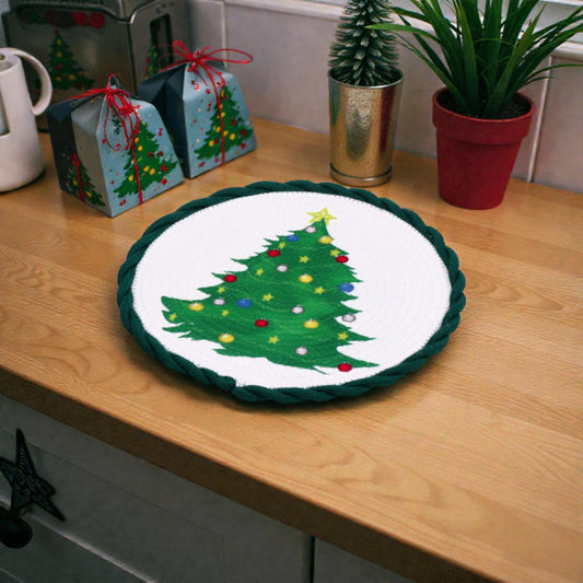 Tovaglietta verde con albero di natale decorativa centro tavola natalizio bianco su piano in legno ambientato in una casa natalizia.