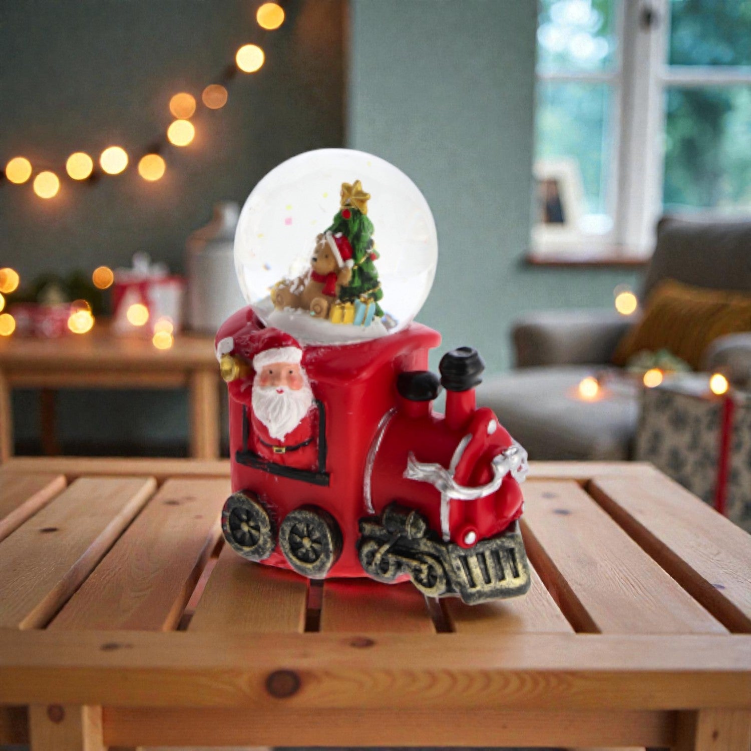 Palla di neve di Natale con base rossa a forma di locomotiva. Ambientata in una casa luminosa.
