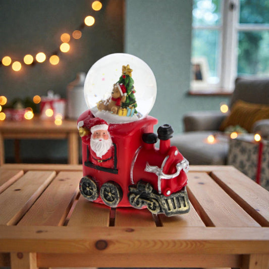 Palla di neve di Natale con base rossa a forma di locomotiva. Ambientata in una casa luminosa.