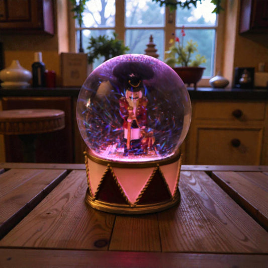 Palla di neve con schiaccianoci con base in resina e luci LED. Ambientata in una casa accogliente.