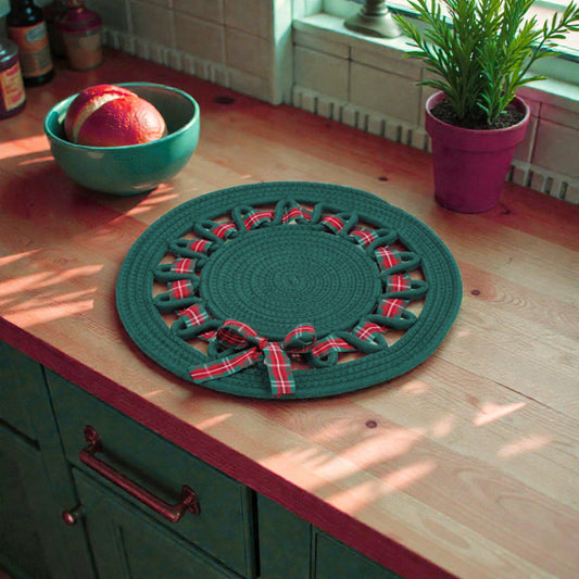 Tovaglietta verde decorativa centro tavola natalizio bianco su piano in legno ambientato in una casa natalizia.