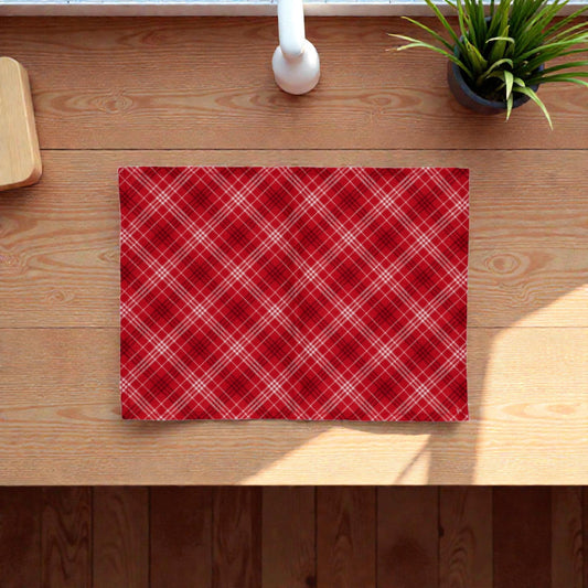 Tovaglietta di Natale rossa Melin in tessuto con motivi natalizi, su un piano in legno