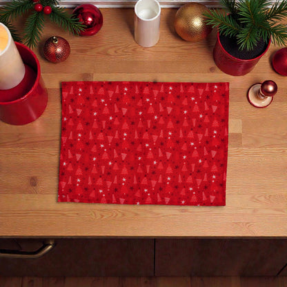 Tovaglietta di Natale rossa Melin in tessuto con motivi natalizi, su un piano in legno